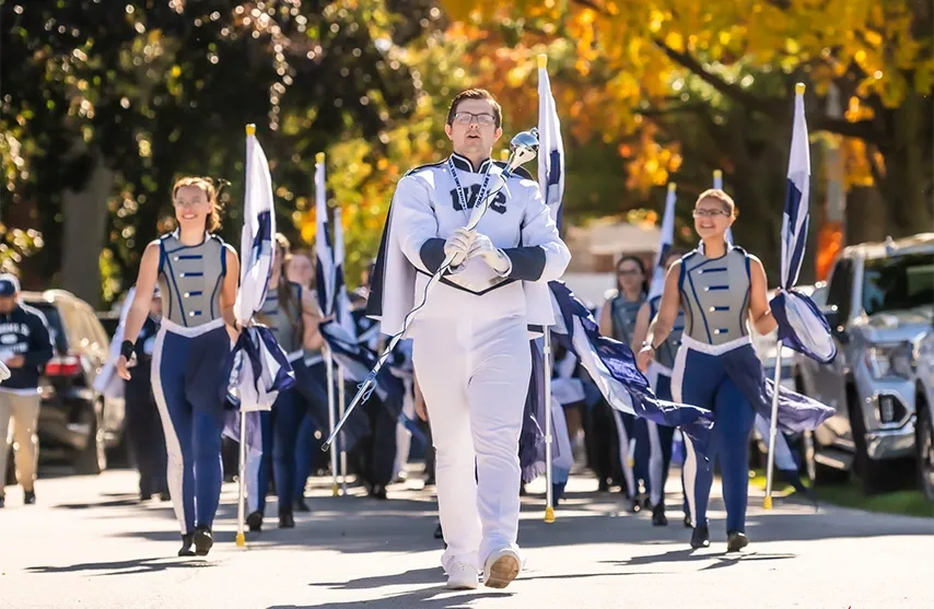 Students marching down the street in a homecoming parade